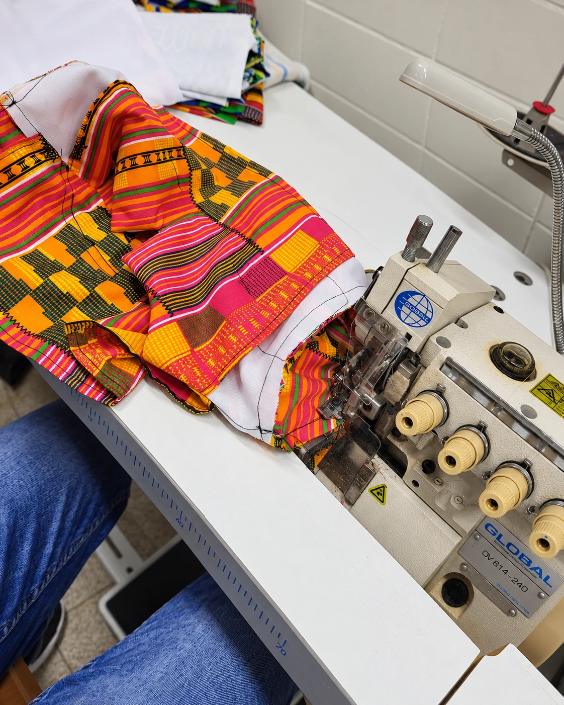 Brightly patterned fabric and white lining beside an overlock sewing machine.